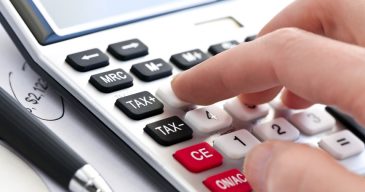Typing  numbers for income tax return with pen and calculator